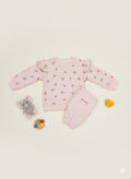 Pink baby outfit with matching pajama and toys on a beige background