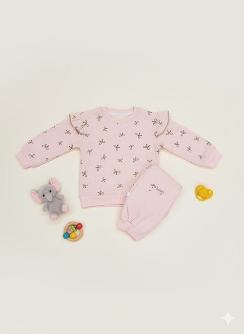 Pink baby outfit with matching pajama and toys on a beige background